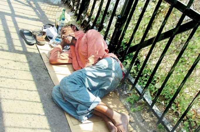 Homeless man sleeping on a city sidewalk - Image via jamaicaobserver.com